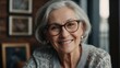 © VistaVisions - Smiling middle aged mature gray haired woman looking at camera, happy old lady in glasses posing at home indoor, positive single senior retired female sitting on sofa in living room headshot portrait