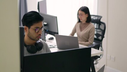 Wall Mural - two asian programmers, a male and a female, are deeply engaged in their work in a modern office sett