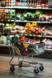 © Emanuel - Supermarket shopping cart filled with groceries in front of store shelves
