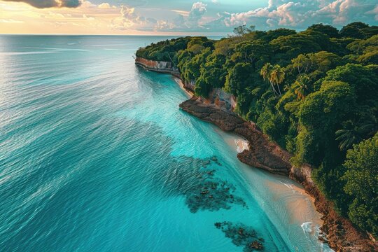 Stunning aerial view of a tropical beach with turquoise waters and lush green cliffs under a serene sky during sunset.