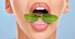 © peopleimages.com - Teeth, lips and dental for hygiene with plant in mouth, female model and leaf for cleaning closeup. Person, tongue and peppermint for fresh breath, health or isolated in blue background for oral care