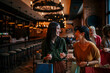 © La Famiglia - Female friends chatting and smiling, walking into a restaurant carrying shopping bags