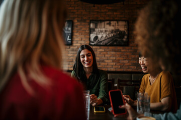 Wall Mural - Four Young Female Friends Meeting Sit At Table In Coffee Shop And Talk