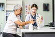 © NanSan - A young Asian female nurse providing healthcare services at her desk, caring for an elderly woman patient. They discuss health checklists and medical advice in a professional setting.