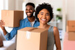 © vasanty - A cheerful couple carries moving boxes into their new home.