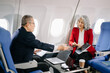 © Nuttapong punna - Business meeting in airplane, asian Mature businessman in private jet is talking with Mature female colleague and documents, business people flying in airplane