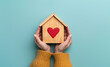 © zchris22 - Avere a cuore la propria casa. Due mani stringono una casetta di legno con un cuore dentro. Spazio per messaggio.