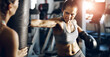 © peopleimages.com - Fitness, woman and boxing bag punch for workout in gym, sports exercise and practice for match. Power, fist and personal trainer with girl athlete, MMA and martial arts in studio for competition