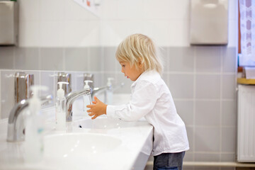 Poster - Little preschool child, blond boy, washing hands in bathroom in kindergarden