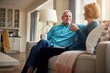 © Reese Coop/peopleimages.com - Senior couple, coffee and smile on couch in conversation, relax or happy memory in home living room. Old man, elderly woman and chat for bonding with tea, love or story in retirement on sofa in house