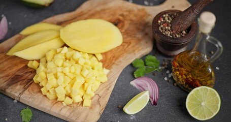 Canvas Print - Woman slicing and chopping mango on a wooden cutting board at domestic kitchen