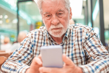 Sticker - Portrait of a caucasian serious man using mobile phone - handsome bearded elderly man sitting thoughtfully while holding mobile phone