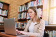 © NonVig/peopleimages.com - Research, typing and woman in library with laptop, education and exam preparation at university. Female student, technology and studying at table for knowledge, communication and learning on internet
