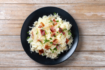 Slovak potato dumplings halusky with steamed sauerkraut and bacon on wooden table. Top view