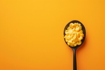Mac and cheese  in black spoon isolated on empty yellow background with space for text or inscriptions, top view
