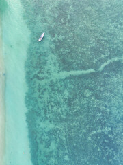 Drone shot birds eye view of a beautiful green sea with boat, waves and sand in Thailand