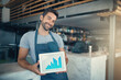 © DoneDeal/peopleimages.com - Man, portrait and restaurant with tablet screen for graph, profit or sales revenue at cafe. Male waiter, barista or business owner with smile for chart, statistics or technology at indoor bistro
