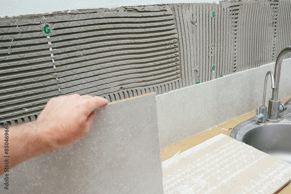 Man remove tile from wall, close-up. A tile has fallen off the wall ...