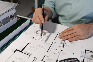 The architect is working on blueprint of important project by using his creativity, the engineer drafts and uses construction design equipment, full of design paperwork on the architect's desk