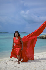 Wall Mural - Lady in red satin flying dress flowing at the beach