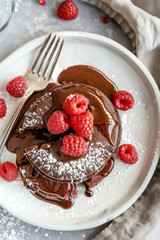 Wall Mural - A delicious chocolate lava cake with a molten center, on a white plate with fresh raspberries