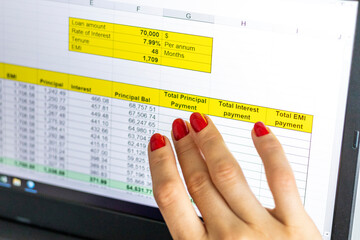 Close up shot of the woman with beautiful hands and manicure, working on the laptop, scrolling touch screen with mortgage loan amortization table open. Finance