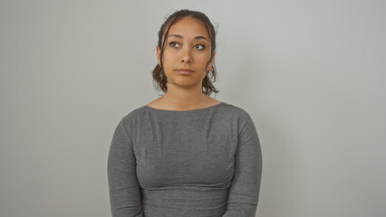 Poster - Portrait of a contemplative young hispanic woman isolated against a white wall, exuding beauty and simplicity.