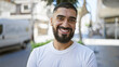 © Krakenimages.com - A handsome young man with a beard smiles outdoors on a sunny city street.