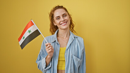 Sticker - Smiling young woman holding a small syrian flag against a yellow background, exuding charm and positivity.