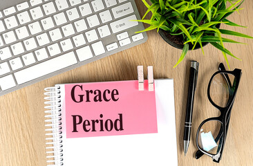 Wall Mural - GRACE PERIOD text pink sticky on notebook with keyboard, pen and glasses