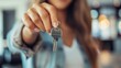 © nilanka - Blurred woman showing the key to her new apartment or female realtor selling the apartment and handing over the key, Focus on the key.
