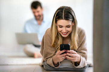 Smiling young woman using mobile phone app playing game, shopping online, ordering delivery