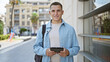 © Krakenimages.com - Smiling young hispanic man with backpack using tablet on sunny urban street
