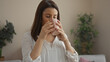 © Krakenimages.com - A beautiful young hispanic woman enjoys a hot drink in an indoor setting, surrounded by greenery, creating a relaxing and serene atmosphere.