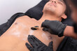 © Mdv Edwards - An esthetician applies hot black charcoal wax to a man's chest during a hair removal procedure at a waxing salon.