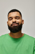 © LIGHTFIELD STUDIOS - Handsome African American man with beard posing in fashionable green attire against vibrant backdrop.