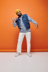 Wall Mural - Handsome African American man in striped shirt and jean jacket posing on a vibrant backdrop.