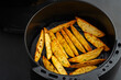 © Kritchai - Homemade Roast Potatoes in an air fryer pot.potato wedges.