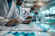 © Ponchita - Scientists Collaborating in a Modern Laboratory Setting, Analyzing Data and Charts, Close Up on Hands with Pen and Paper