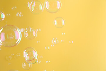 Poster - Beautiful transparent soap bubbles on yellow background, space for text