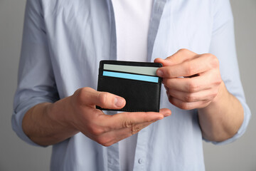 Wall Mural - Man holding leather business card holder with cards on grey background, closeup