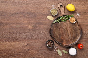 Canvas Print - Cutting board, spices, lemon and tomato on wooden table, flat lay. Space for text