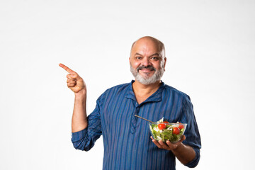 Senior Indian asian man eating fresh salad. Mature male having healthy snack, healthcare, diet concept.