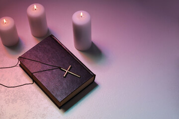 Wall Mural - Cross, burning candles and Bible on textured table in color lights, above view with space for text. Religion of Christianity