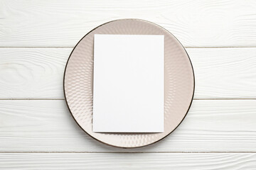 Wall Mural - Empty menu and plate on white wooden table, top view. Mockup for design