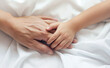 © Leonardo - Mani di adulto e bambino che si stringono e si accarezzano in un letto di una stanza di ospedale