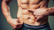 © tiagozr - Close-up of a muscular male torso pointing at abs. Personal trainer.