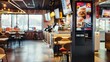 © Prostock-studio - A modern fast food restaurant with a self-service kiosk displaying a menu of burgers, and a dining area with tables and chairs.