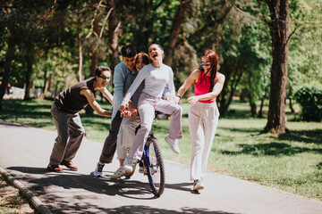 Poster - A joyful moment as three friends share fun on a bicycle ride through a sunny, green park over the weekend