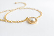 © Rysak - Gold Chain Necklace with Pearl Pendant on White Background